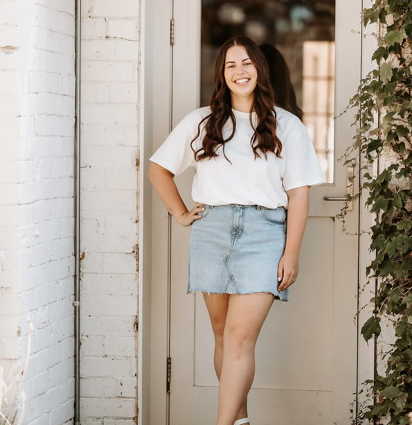 Liv from Gracie Creative standing in front of a door outside, posing for the camera.