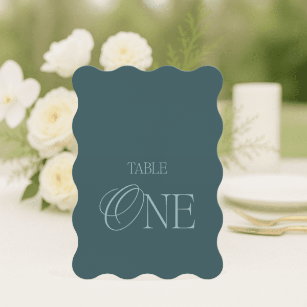 So Chic wedding table number in wave shape featuring romantic, modern fonts and soft colour palette, styled for an elegant reception table.