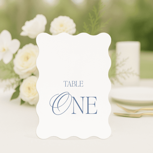 So Chic wedding table number in wave shape featuring romantic, modern fonts and soft colour palette, styled for an elegant reception table.