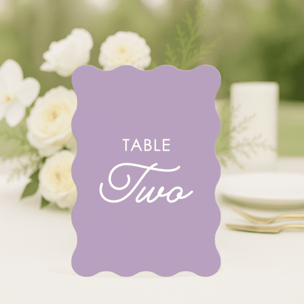 Love Bug wedding table number in wave shape featuring romantic, modern fonts and soft colour palette, styled for an elegant reception table.