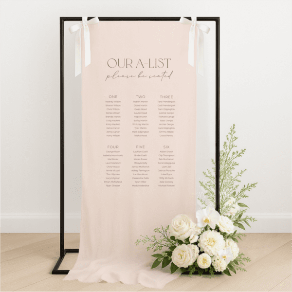 Linen wedding seating chart hanging on a black metal frame with white ribbon, featuring merlot text for with heading 'our a-list', styled with white roses and greenery at the base – semi-custom signage by Gracie Creative, Australia.